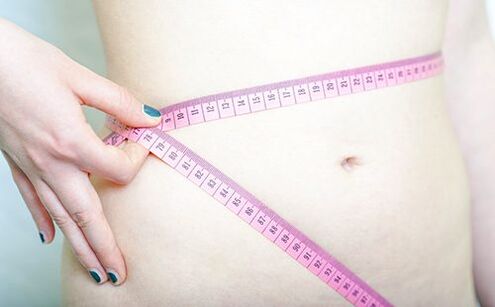 Момиче измерва талията си, за да запише резултатите от спазването на диетата на Дюкан